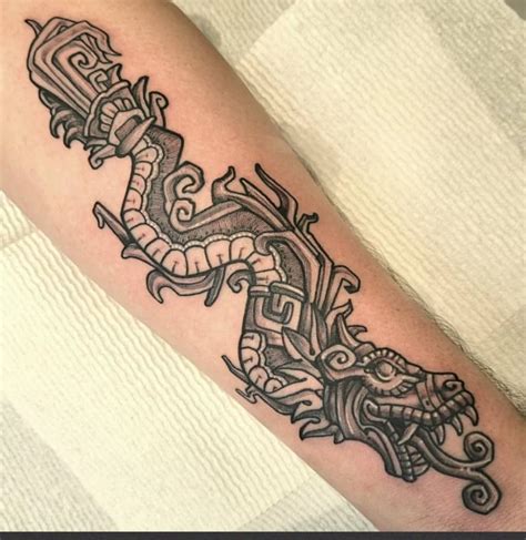 Aztec quetzalcoatl tattoo design - This Quetzalcoatl tattoo boasts a striking monochromatic design that artfully captures the essence of the feathered serpent deity from Mesoamerican culture. The meticulous line work emphasizes intricate patterns and Aztec motifs, giving the piece a strong sense of authenticity and cultural reverence. 